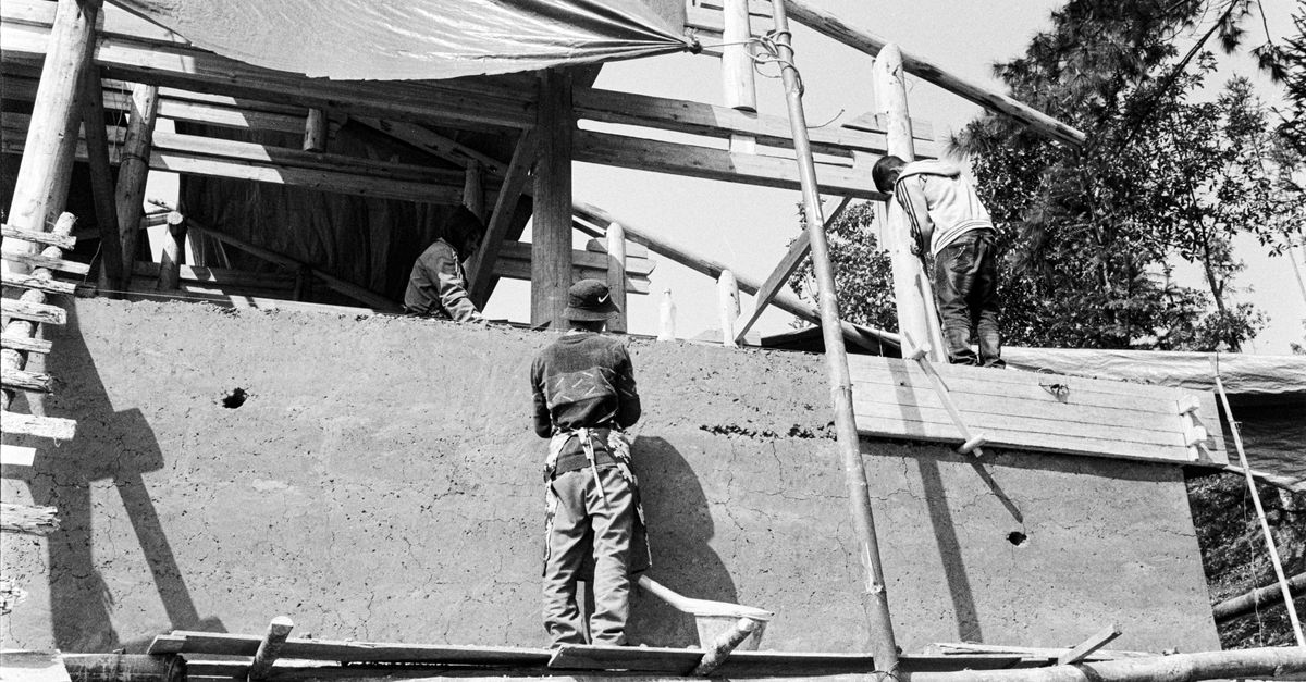 Monochrome image of workers at a construction site with scaffolding.